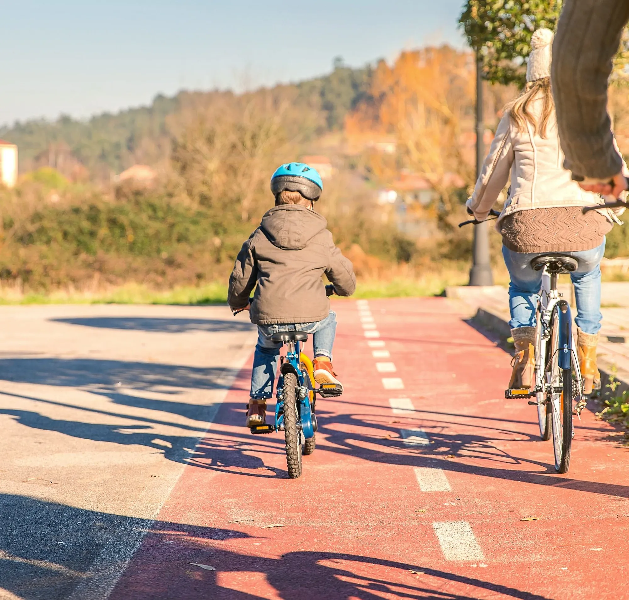 Madre e hijo pedaleando por un carril bici rojo